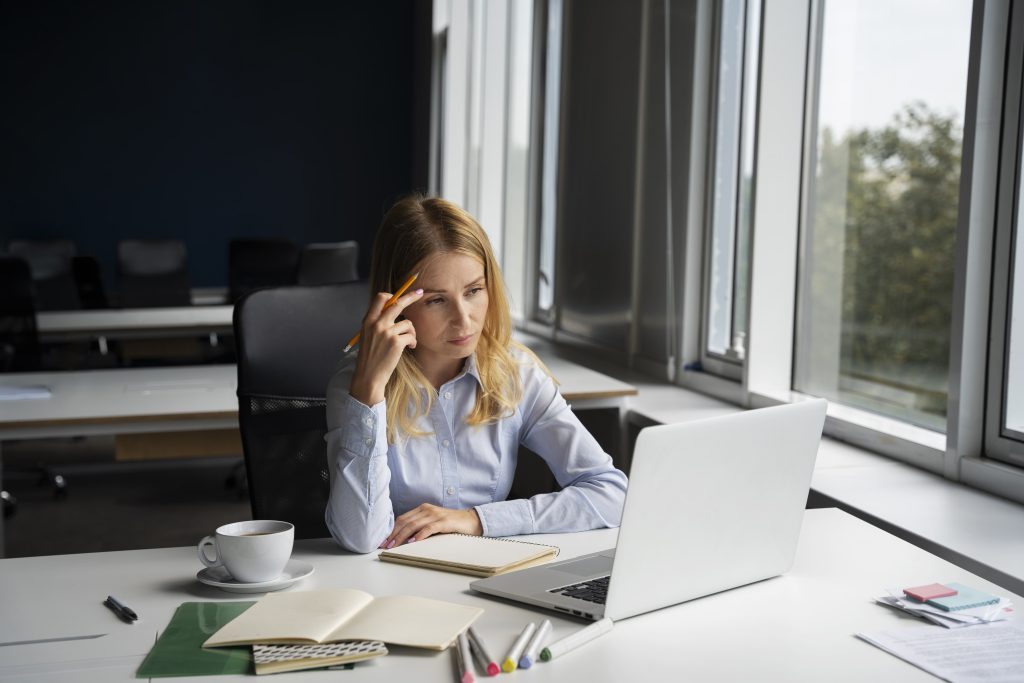 Femme assise à son bureau, tête dans les mains, en surcharge mentale qui n'arrive pas à déconnecter